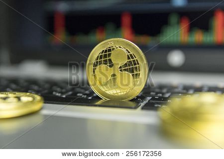 Golden Ripple Coin With Gold Coins Lying Around On A Black Keyboard Of Silver Laptop And Diagram Cha