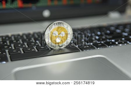 Golden And Silver Ripple Coin On A Black Keyboard Of Silver Laptop And Diagram Chart Graph On A Scre
