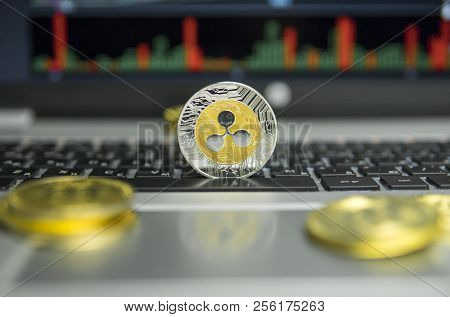 Golden And Silver Ripple Coin With Gold Coins Lying Around On A Black Keyboard Of Silver Laptop And 