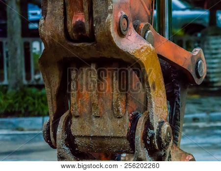 Closeup Of Actuator Arm Of Backhoe In Front Of City Street