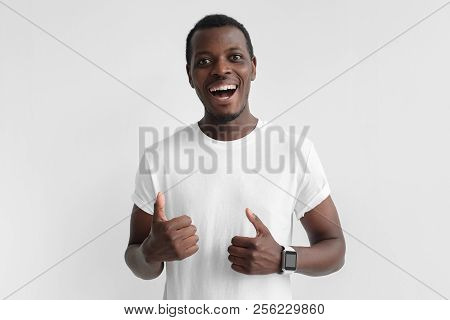 Young Afrcian American Man Isolated On Gray Background Showing Thumps Up With Positive Emotions Of C