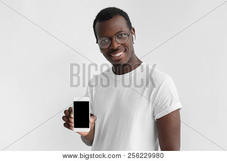 Young Afrcian American Man Smiling Isolated On Gray Background, Holding And Showing Vertical Blank S
