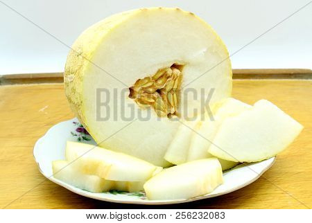 Slices Of Melon Lying On A Plate And A Wooden Board.