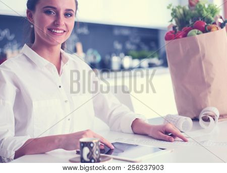 Young woman planning expenses and paying bills on her kitchen