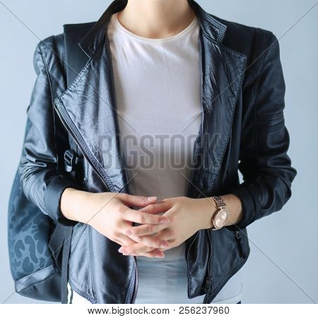 portrait of beautiful young brunette woman in stylish black jacket on gray.