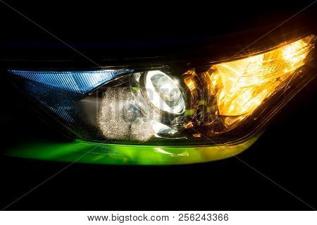 Front Headlight On A Modern Green Car At Night. Low Beam And Turn Signal Or Blinker Lit.