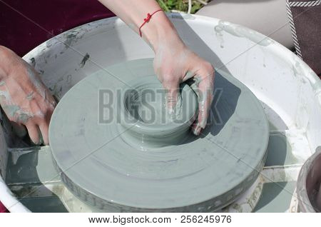 Ceramic Workshop - The Girl Makes A Pot Of Clay On A Potter's Wheel. Hands Closeup