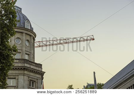 A Tower Crane Behind A Tall Building At Dusk.