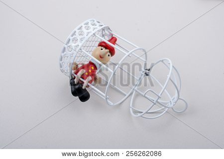 Metal Cage And Little Puppet Pinocchio Made Of Wood
