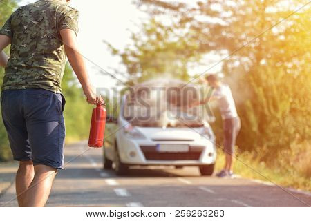 Brave Man With Fire Extinguisher Going To A Car Incident On The Road With Smoke On The Engine