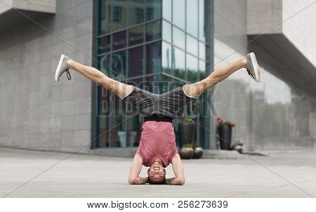 Young Man Doing Yoga Headstand Exercise On Building Background