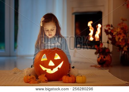 Kids Carving Pumpkin On Halloween At Home Sitting Next To Fireplace In Living Room Decorated With La