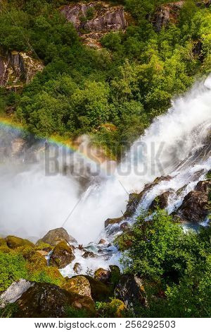 Waterfall And Rainbow On The Way To Briksdal Or Briksdalsbreen Glacier In Olden, Norway And Green Mo