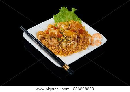 Mi Xao Hai San Stir-fried Noodles Asian Meals On Triangle Plate Isolated On Black. Served With Chops