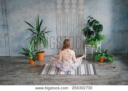 Young Woman Sitting Back In Easy Pose And Meditates In Boho Interrior. Yoga At Home Concept.