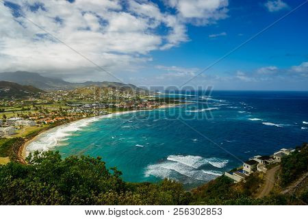 A View Over St. Kitts Island With Residential Area And Beaces On The Foreground And Lush Green Hills