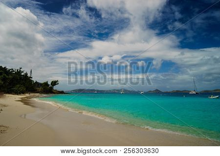 Long Beach With Yacht Floating On The Clear Waters Of The Caribbean
