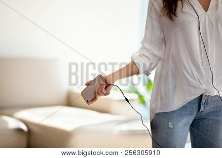 Closeup Of Woman Holding Smartphone Listening To Music In Headph