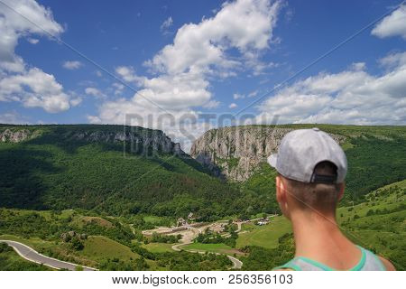Summer Hiking In The Mountains. Young Tourist Man In A Cap Looking On Mountain