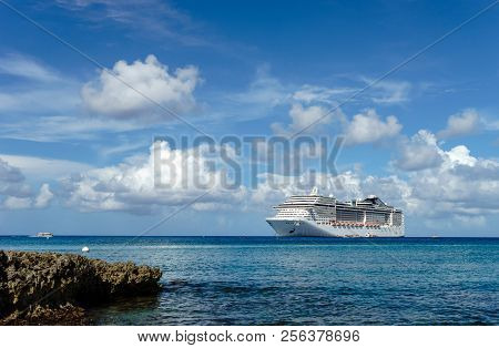 Cruise Ship In Crystal Blue Water With A Rock On The Front