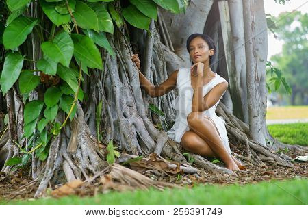 A Beautiful African-looking Girl With Black Short Hair And White Dress Pousing Near The Big Beautifu
