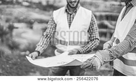 Builders On Residential Construction Site Looking The Building Project  - Workers Talking About Thei