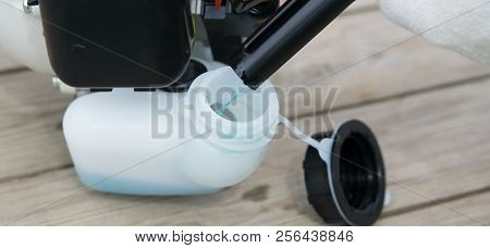 On The Street, Fill The Tank Of Benzo Mower With Blue Fuel Mixture, On A Wooden Background.