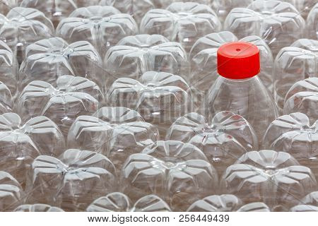 Single Unique Plastic Bottle With Red Cap Amongst Many Upturned Clean Empty Bottles In A Concept Of 