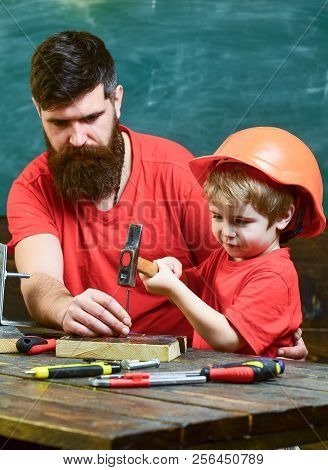 Father With Beard Teaching Little Son To Use Tools, Hammering, Chalkboard On Background. Boy, Child 