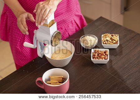 High Angle View Of A Woman Grinding Biscuits In A Biscuit Grinding Machine. Focus On The Buscuits In