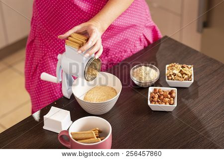 High Angle View Of A Woman Putting Biscuits In A Biscuit Grinding Machine, Preparing Ingredients For