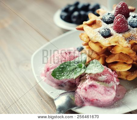 Plate of belgian waffles with ice cream  and fresh berries - raspberries and blueberries.top view close-up.