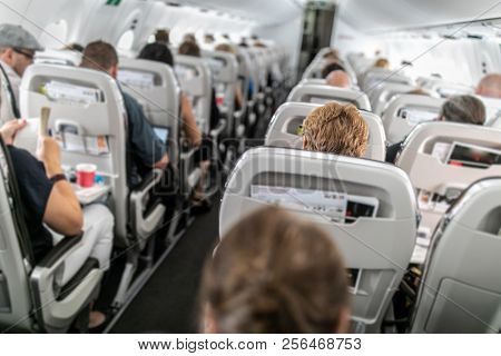 Interior of commercial airplane with passengers in their seats during flight.