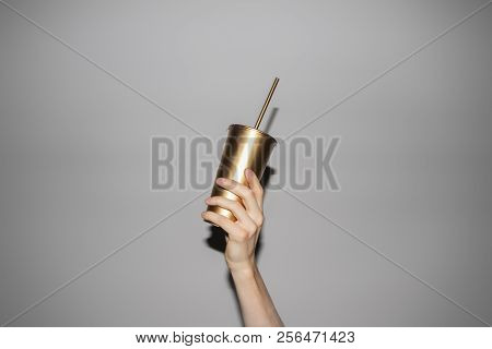 Conceptual Photo Of Hand Holding Golden Soda Cup With Straw.