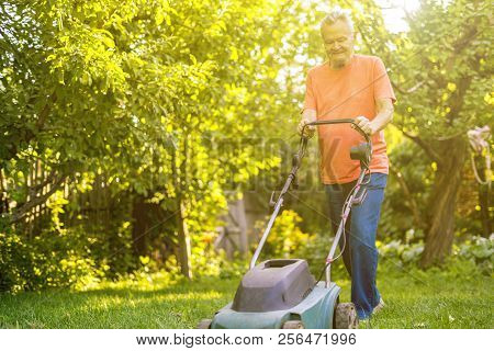 Portrait Of Eldery Senior Man Working In The Summer Garden Walking On Grass Field