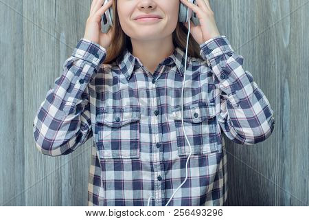 Young Teenage Girl In Checkered Shirt Touching Headphones And Listening To Her Favourite Song
