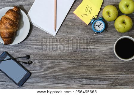 Cropped Background Of Office Accessorise. Notepad, Cup Of Coffee, Smartphone, Earphones, Croissant