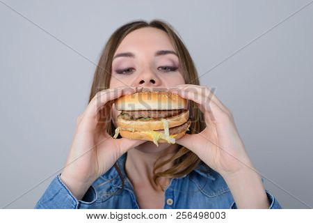 Concept Of Eating Unhealthy Snacks. Hungry Woman Biting Big Tasty Humburger In Her Lunch Break; Isol