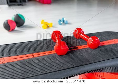 Red Modern Dumbbells In The Foreground On A Step Platform