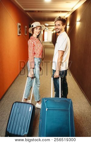 Smiling couple with suitcase in hotel hallway