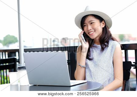 Young Asian Woman Working With Laptop Computer And Talking Phone At Cafe Outdoors Background, Poeple