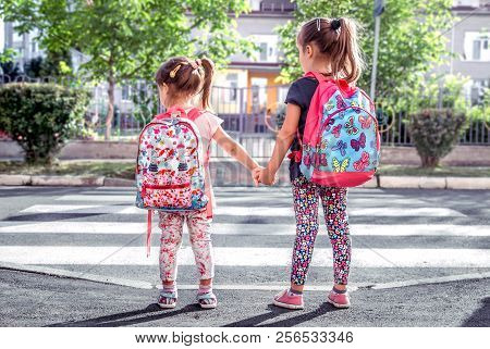 Children Go To School, Happy Students With School Backpacks And Holding Hands Together, Cross The Ro