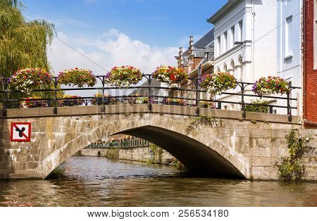 Old Bridge With Colorful Flowers Over The Canal In The Historical Medieval City.