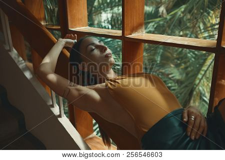 Preety Woman Relaxing While Lying On A Wooden Stair Railing Near