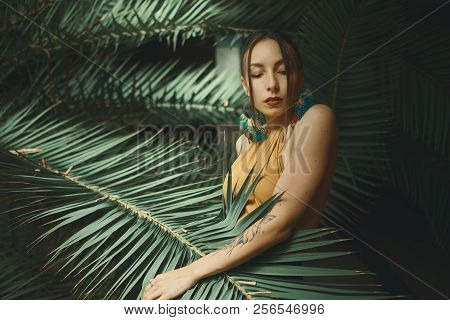 Beautiful Young Woman Posing On A Background Of Exotic Palm Leav