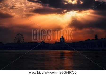 Sun Beams Trough The Clouds In A Cloudy Sunset Through Ferris Wheel And Paseo Del Muelle Uno In Port