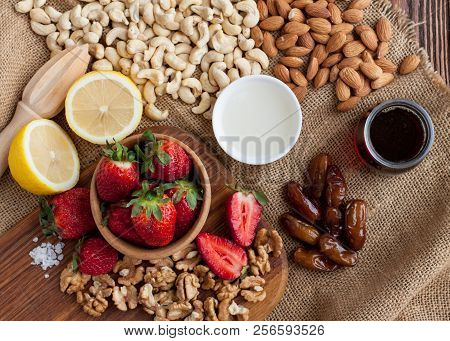 Almonds, Cashews, Walnuts, Dates, Strawberries, Lemon, Coconut Butter, Maple Sirup, Salt On Wooden T