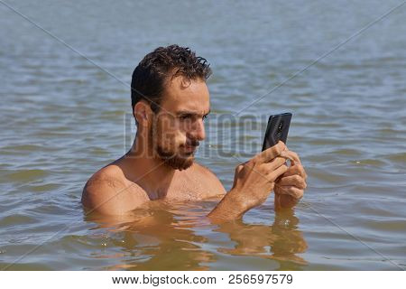 Using smartphone obsessively at the beach on vacation