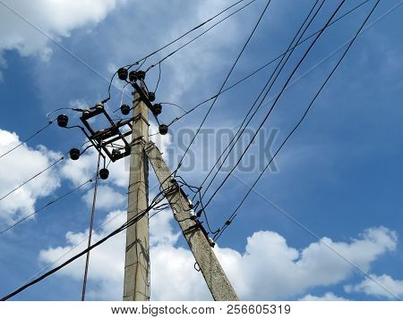 Power Line Support Against Blue Sky With White Clouds. Power Pole With Electrical Wires And Capacito