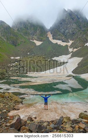 Partially Frozen Didighali Lake With A Young Man And Mountain Pass In The Background In Caucasus Mou